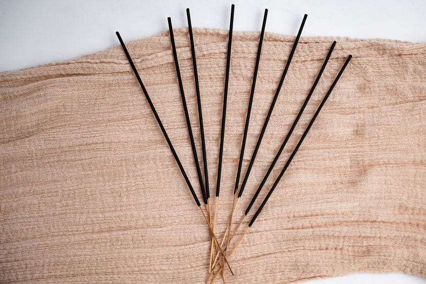Black incense sticks on a textured beige surface